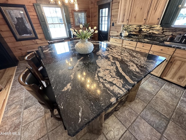 kitchen featuring dark stone countertops, a kitchen bar, and wood walls