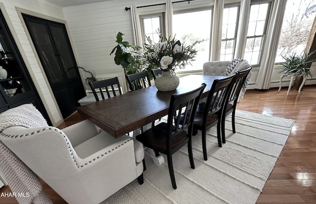 dining room featuring wood-type flooring, crown molding, and baseboard heating