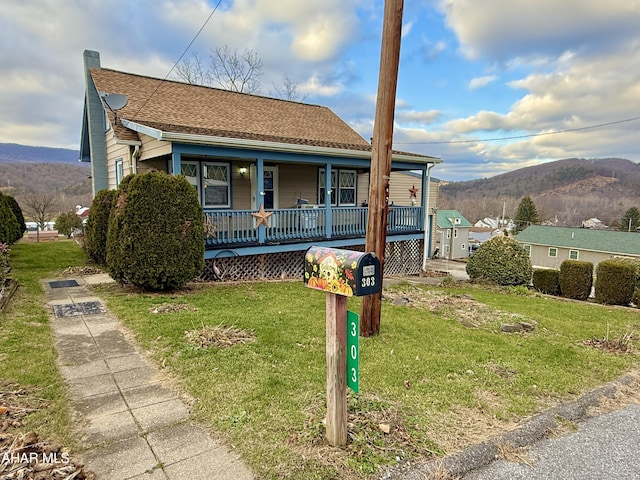 view of front of property featuring a mountain view, a front lawn, and covered porch