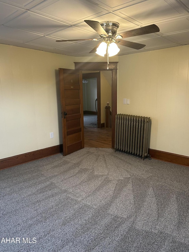 empty room featuring carpet, radiator, and ceiling fan