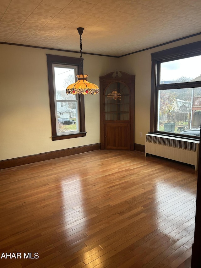 unfurnished dining area with radiator heating unit and hardwood / wood-style floors