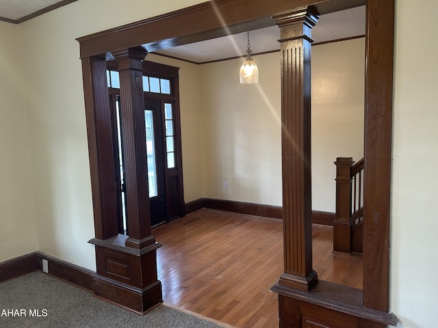 foyer featuring wood-type flooring, decorative columns, and ornamental molding