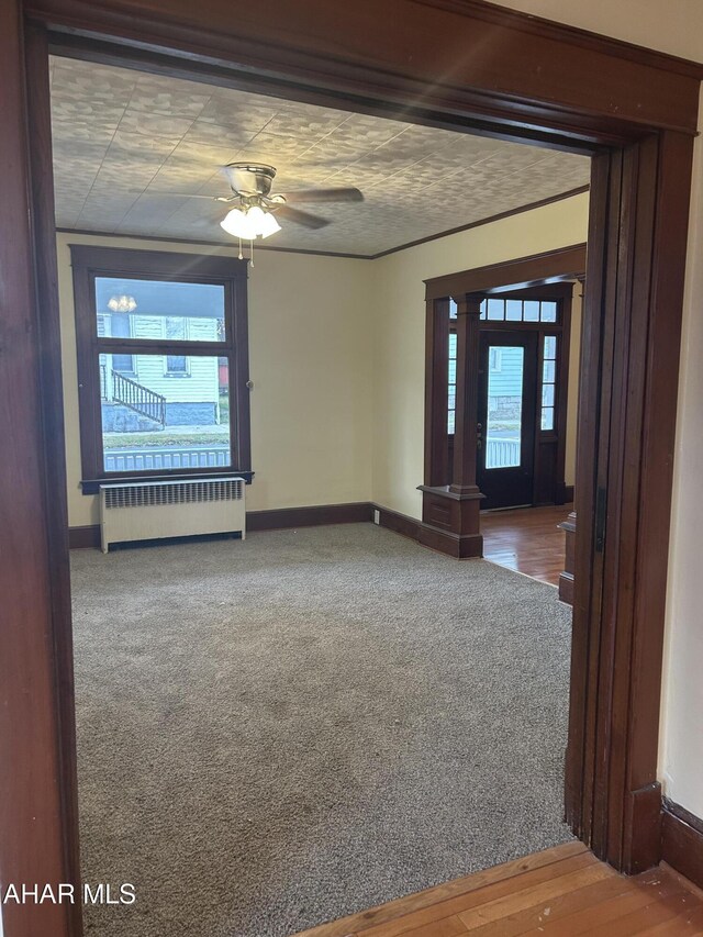 spare room with ceiling fan, radiator heating unit, a healthy amount of sunlight, and hardwood / wood-style flooring