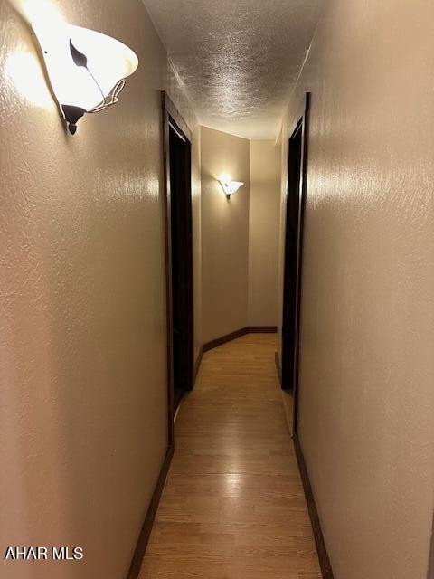 hall featuring a textured ceiling and light hardwood / wood-style floors