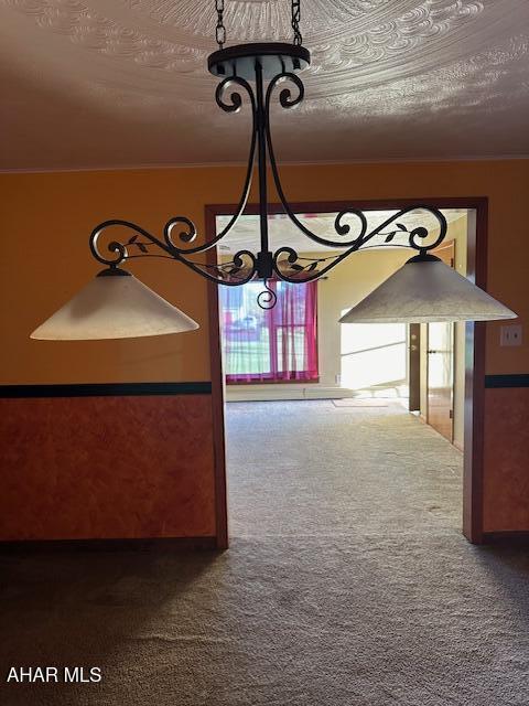 unfurnished dining area with carpet flooring, a textured ceiling, and a notable chandelier