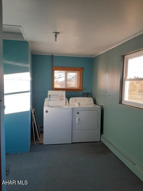 laundry area featuring dark colored carpet, plenty of natural light, separate washer and dryer, and a baseboard heating unit