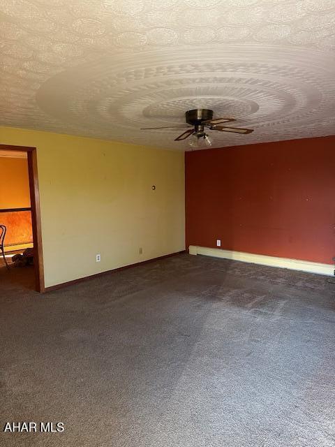 carpeted empty room with ceiling fan and a textured ceiling