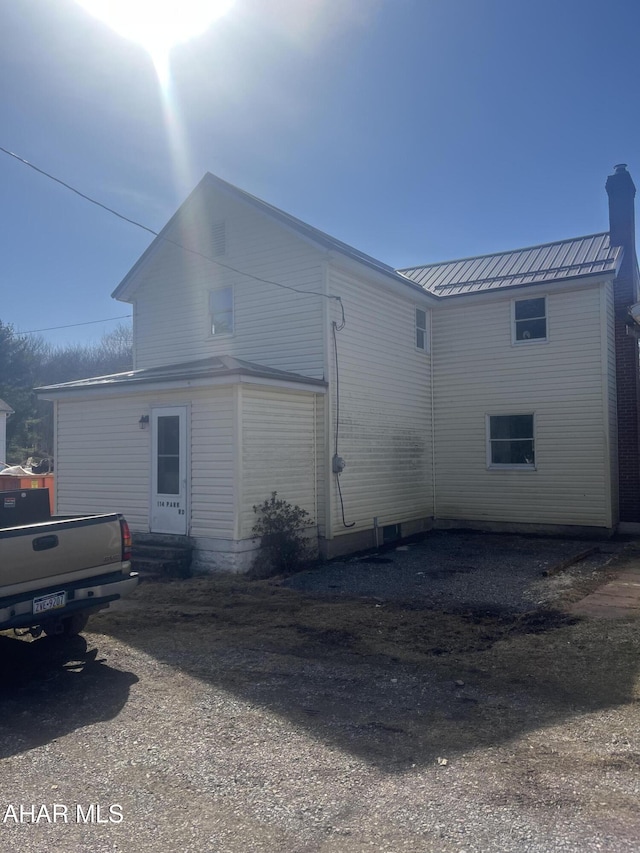 view of home's exterior with a chimney, entry steps, and metal roof