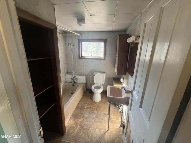 full bathroom featuring tile patterned floors, washtub / shower combination, toilet, and a sink