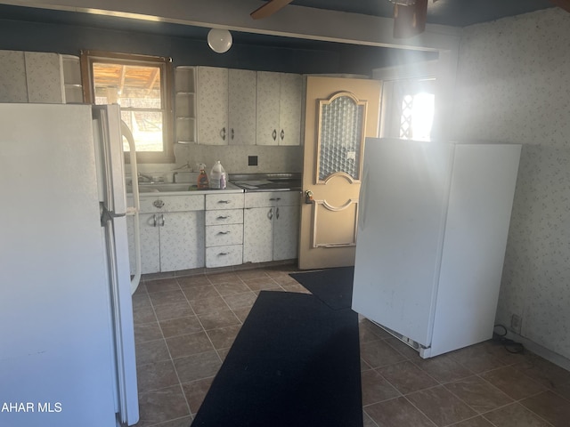 kitchen featuring open shelves, wallpapered walls, dark tile patterned flooring, and freestanding refrigerator