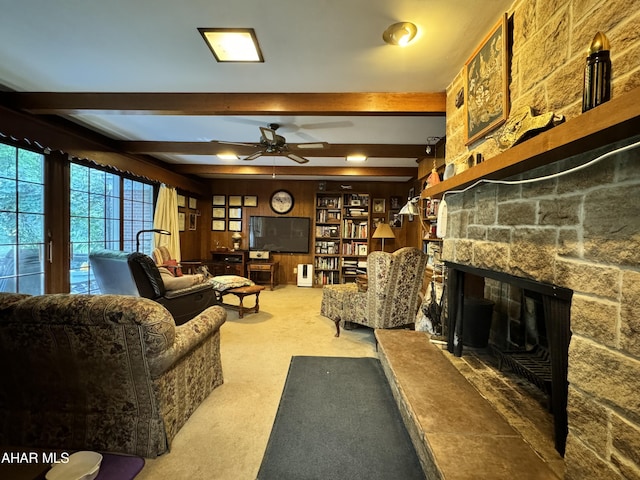 living room featuring a fireplace, ceiling fan, beamed ceiling, carpet floors, and wood walls