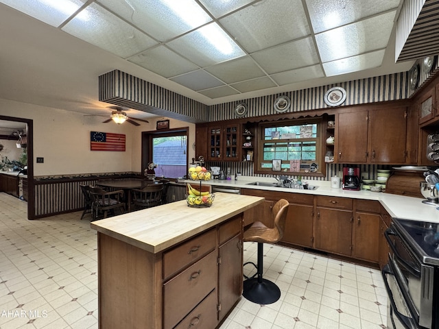 kitchen with electric range, ceiling fan, sink, butcher block countertops, and dark brown cabinets