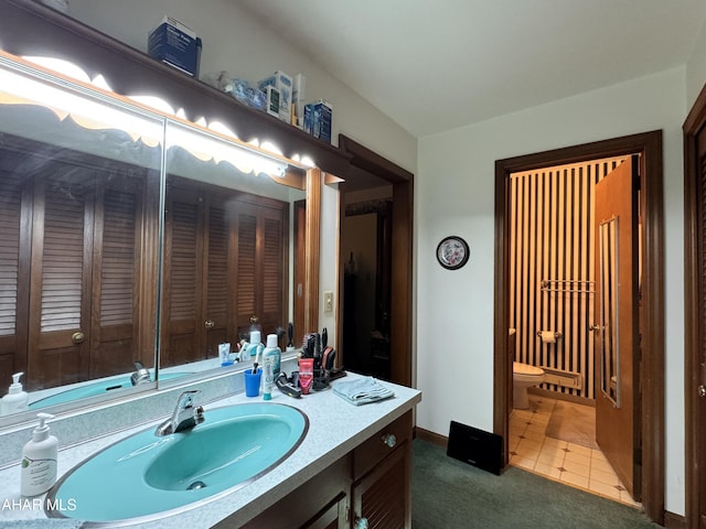 bathroom with toilet, vanity, and tile patterned floors