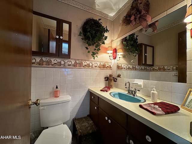 bathroom featuring vanity, toilet, and tile walls