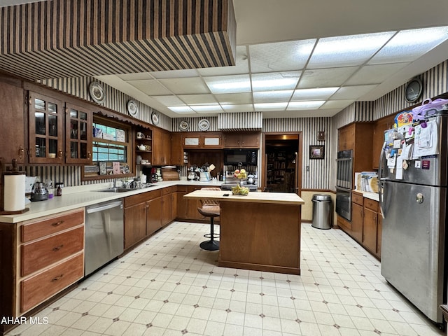 kitchen with a breakfast bar, a paneled ceiling, stainless steel appliances, and sink