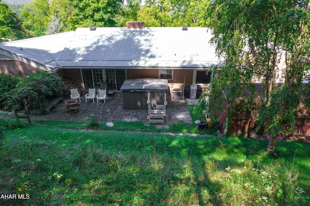 back of property featuring a hot tub and a patio area