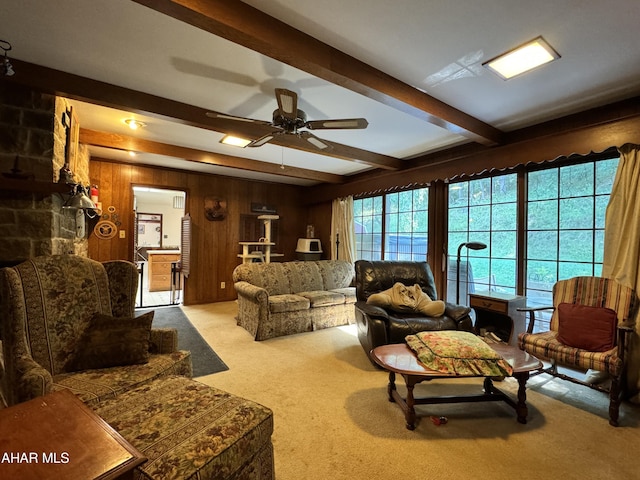 living room featuring light carpet, wooden walls, beamed ceiling, and ceiling fan