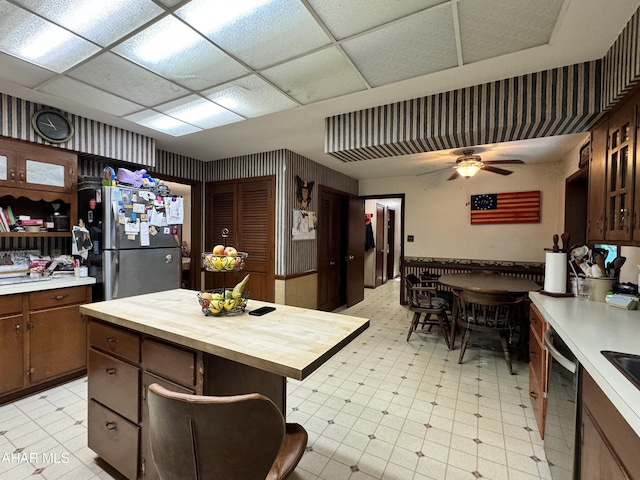 kitchen featuring wood counters, a paneled ceiling, dark brown cabinets, stainless steel appliances, and ceiling fan