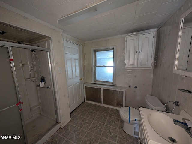 bathroom with a shower stall, radiator, toilet, vanity, and tile walls