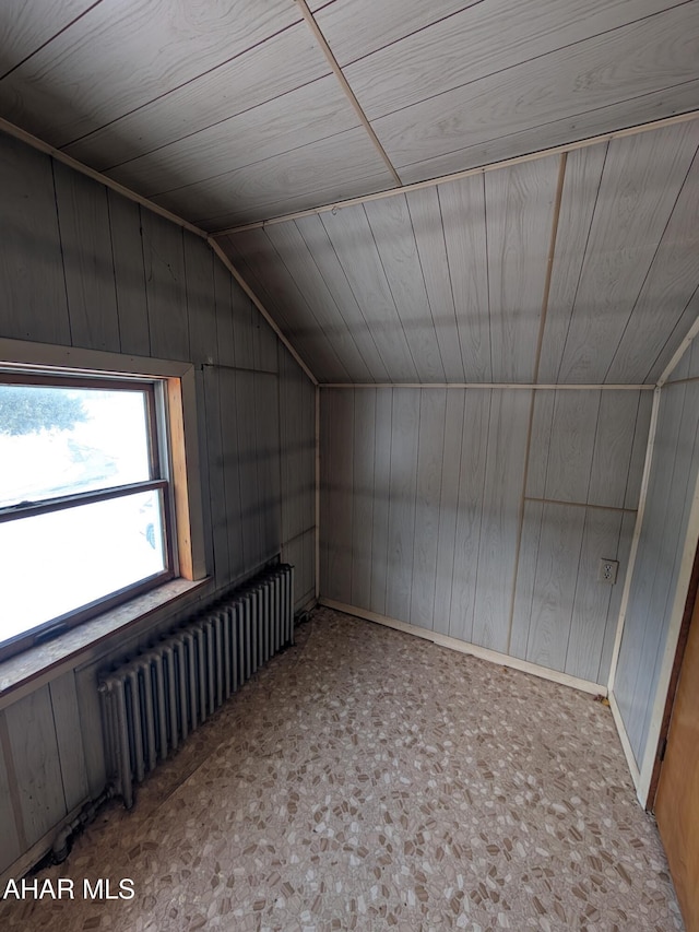 bonus room with lofted ceiling, wooden walls, radiator, and carpet floors