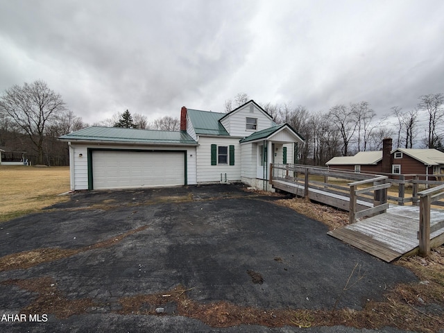 view of front of house with aphalt driveway, metal roof, and a garage