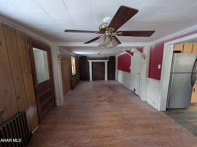 hall with radiator heating unit, wood finished floors, wainscoting, and ornamental molding