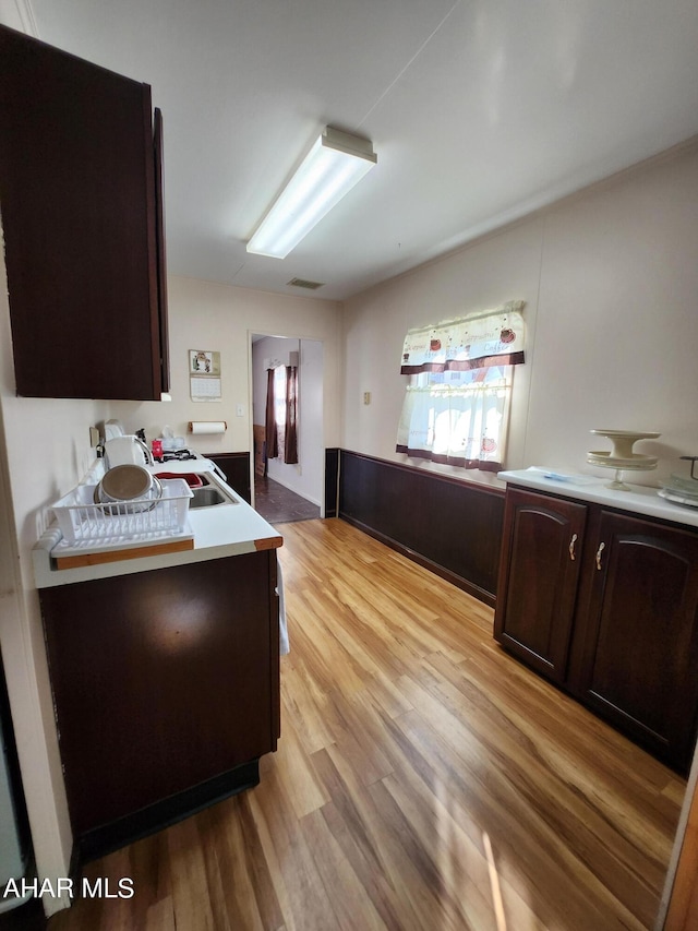 kitchen with dark brown cabinetry, sink, and light hardwood / wood-style floors