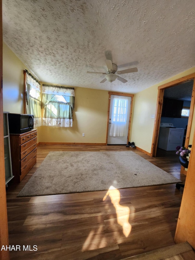 unfurnished living room with a textured ceiling, ceiling fan, and dark wood-type flooring