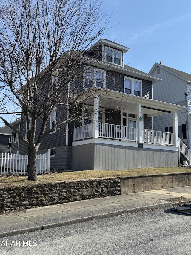 traditional style home featuring a porch and fence