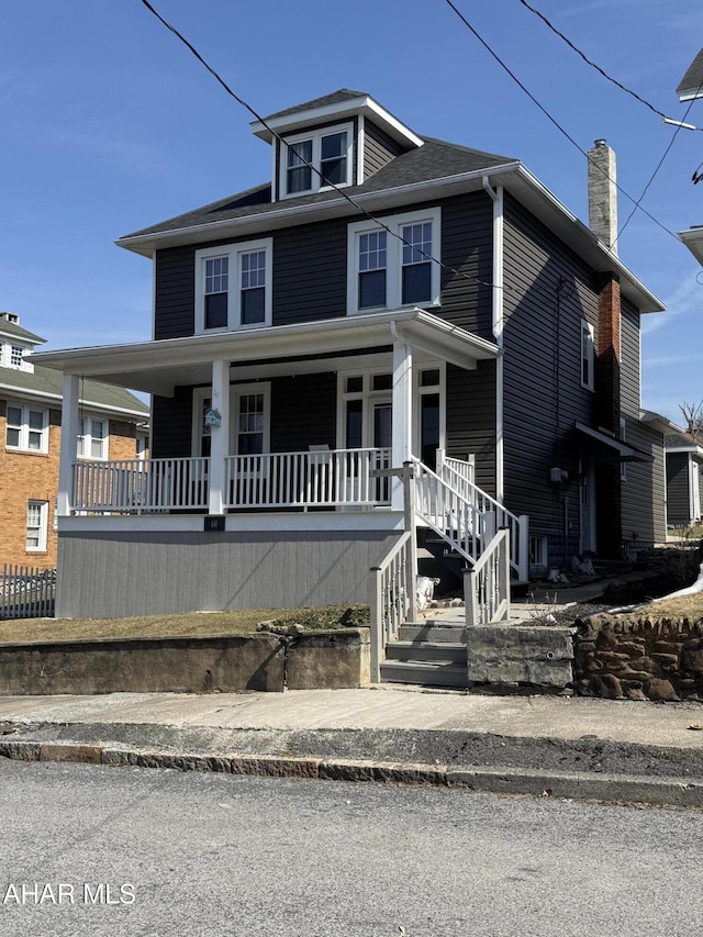 american foursquare style home featuring a porch and a chimney