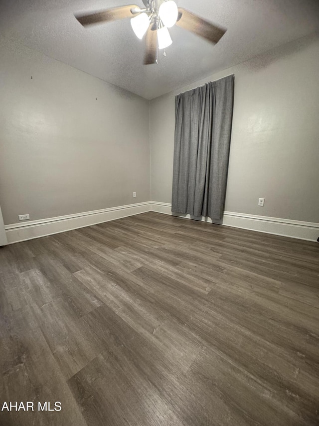 unfurnished room with a textured ceiling, baseboards, dark wood-type flooring, and a ceiling fan