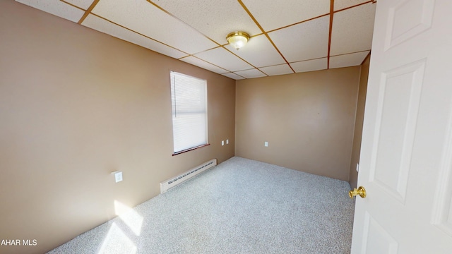 empty room with carpet, a baseboard radiator, and a drop ceiling