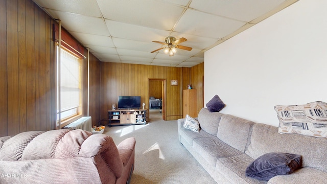 living room with wood walls, radiator heating unit, carpet flooring, and a paneled ceiling