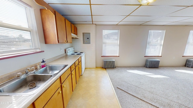 kitchen with white range with electric cooktop, brown cabinetry, radiator, under cabinet range hood, and a sink