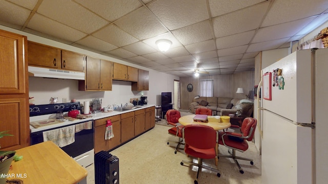 kitchen featuring white appliances, under cabinet range hood, light countertops, and a drop ceiling