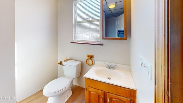 half bath featuring a drop ceiling, vanity, and toilet