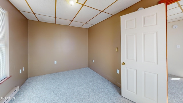 spare room with carpet flooring, a drop ceiling, and baseboard heating