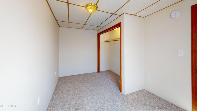 unfurnished bedroom featuring carpet floors, a closet, and a drop ceiling