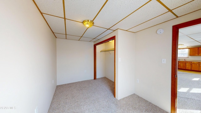 interior space featuring a paneled ceiling, light carpet, and a closet