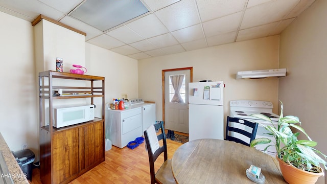 interior space with a paneled ceiling, light wood finished floors, and separate washer and dryer