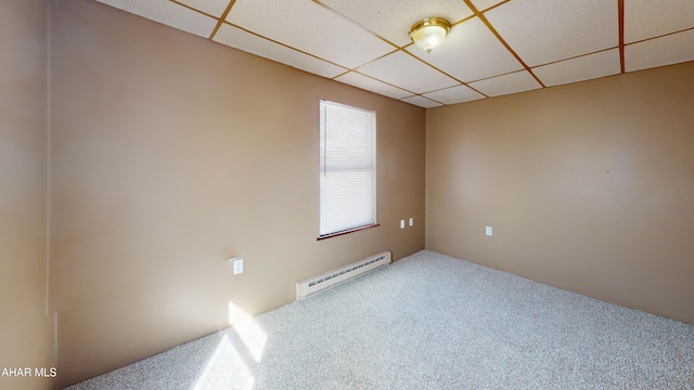 carpeted spare room featuring a baseboard heating unit and a drop ceiling