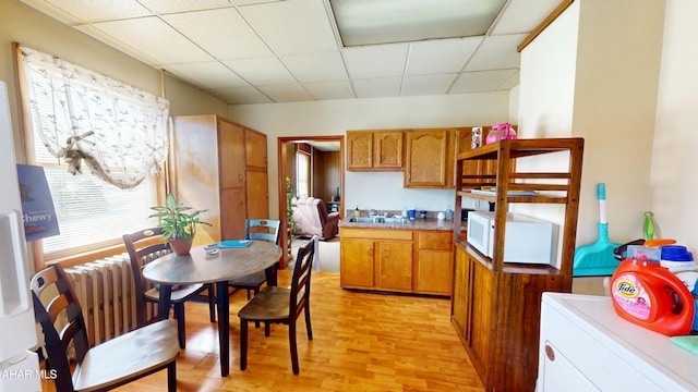 kitchen with a drop ceiling, a sink, light wood-style floors, washer / clothes dryer, and brown cabinetry