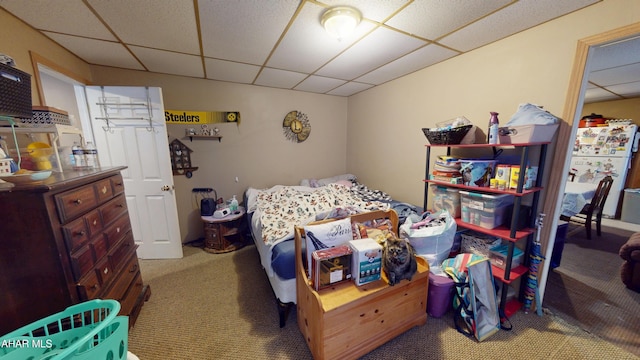 carpeted bedroom featuring a paneled ceiling and freestanding refrigerator