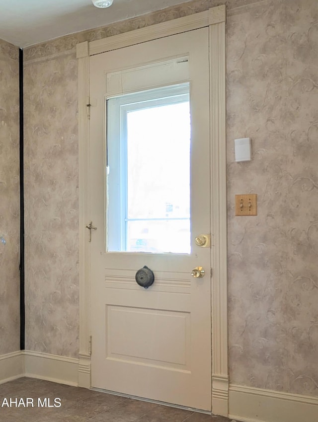 doorway featuring baseboards and wallpapered walls