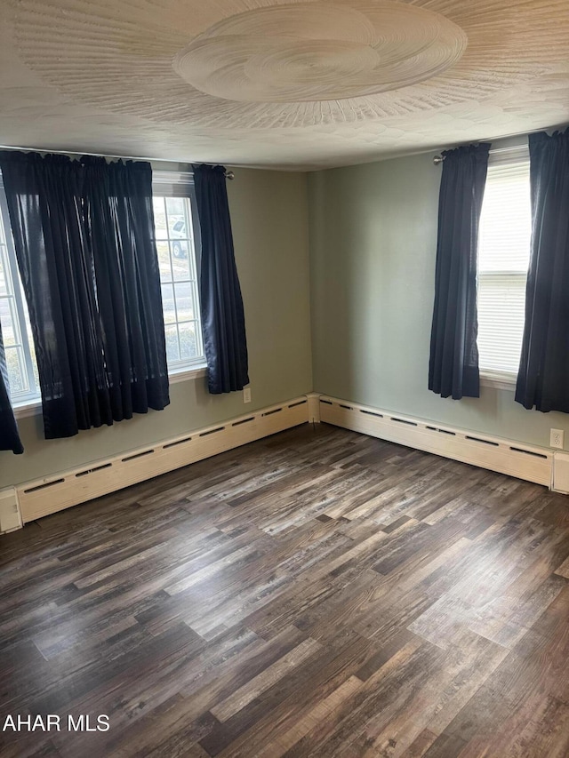 empty room with dark hardwood / wood-style floors and a healthy amount of sunlight