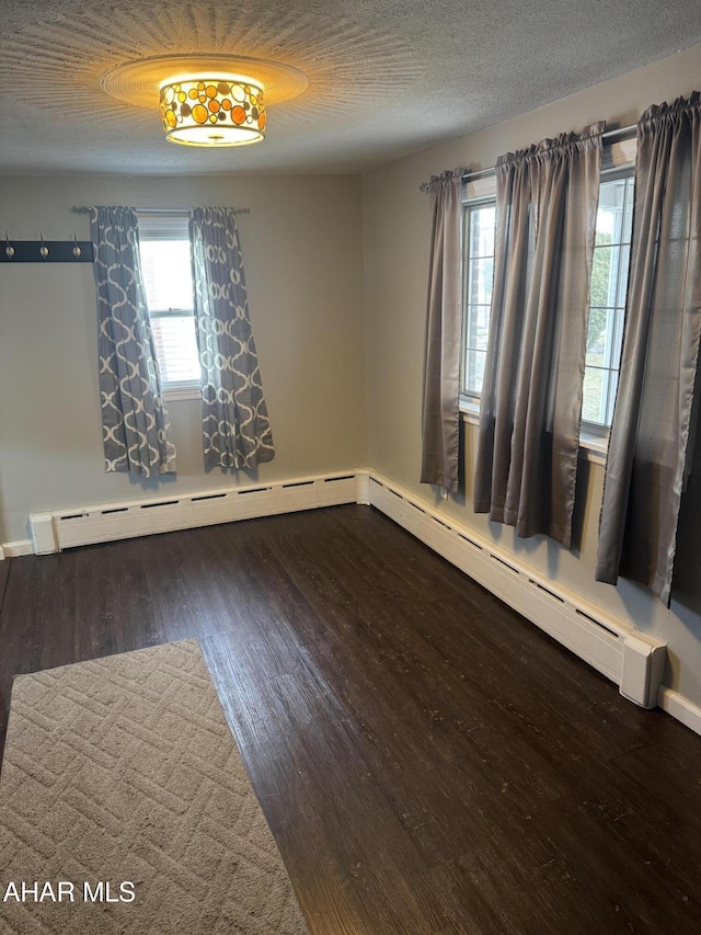 unfurnished room featuring baseboard heating, dark hardwood / wood-style floors, and a textured ceiling