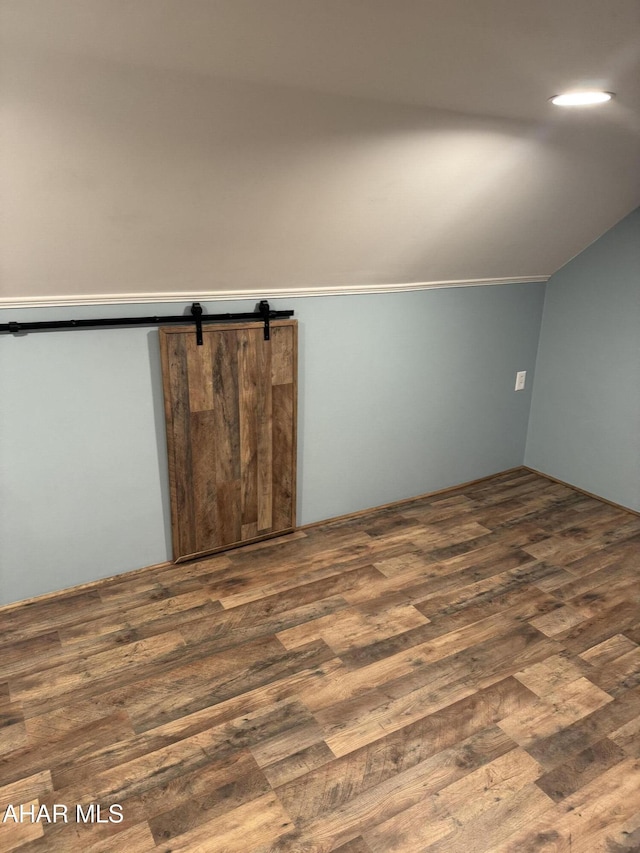 bonus room featuring vaulted ceiling, a barn door, and dark hardwood / wood-style floors