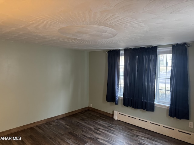 spare room with dark hardwood / wood-style flooring and baseboard heating