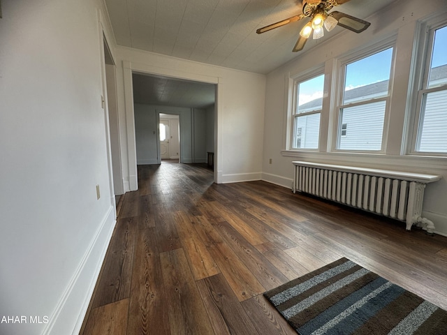 empty room featuring ceiling fan, radiator heating unit, and dark hardwood / wood-style floors