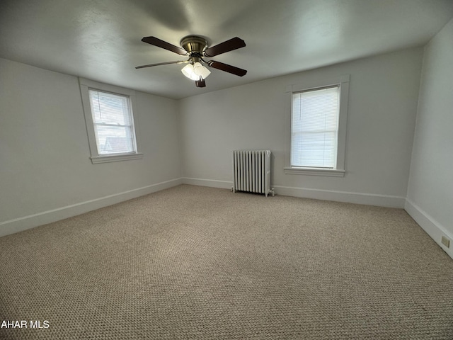 unfurnished room with radiator, ceiling fan, and light colored carpet